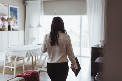 Rear view of woman standing on chair