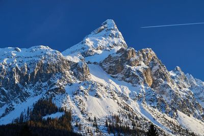 Low angle view of snowcapped mountain against blue sky