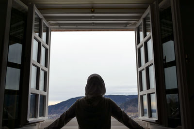 Rear view of woman looking through window