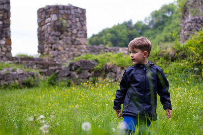 Boy standing amidst grassy field