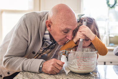 Grandpa helping granddaughter cook pancakes for breakfast