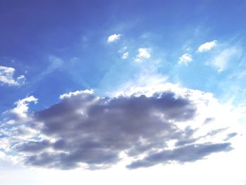 Low angle view of sunlight streaming through clouds