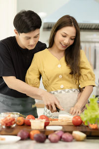 Happy young woman standing on cutting board at home
