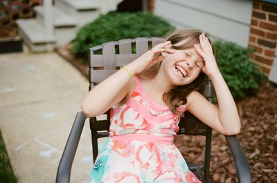 Happy girl sitting on chair at yard