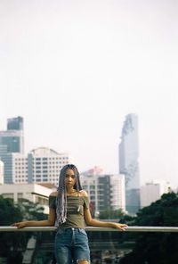 Woman standing against buildings in city against sky