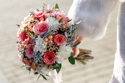 The bride holds in her hands a bouquet of roses, carnations, eucalyptus and cineraria sprigs