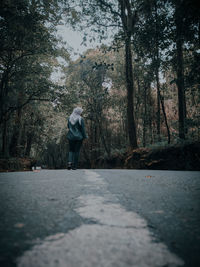 Rear view of man standing by trees in forest