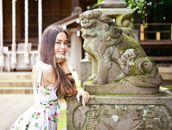 Young woman with statue against shrine background