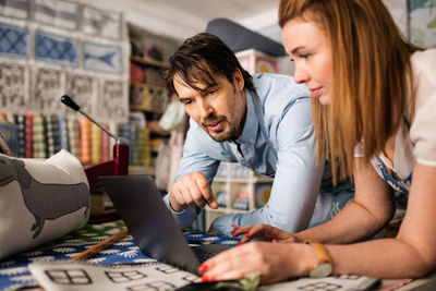 Male and female owners using laptop in fabric shop