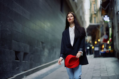 Portrait of young woman standing against wall