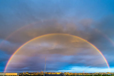 Idyllic shot of rainbow over cityscape against cloudy sky