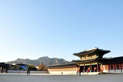 People at temple against clear blue sky