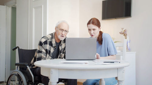 Nurse and senior man looking at laptop in office