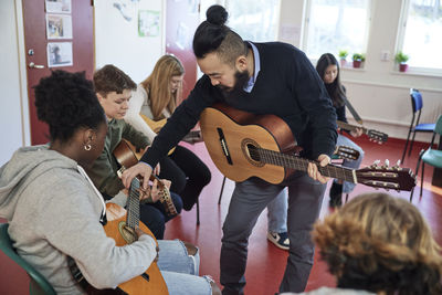 Teenagers attending guitar lesson