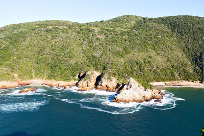 People on rocks against clear sky