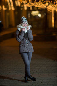 Woman standing on road in city at night