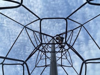 Young girl climbs playground rope structure 