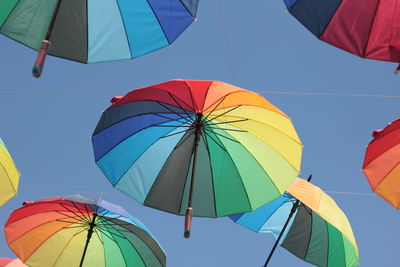 Low angle view of umbrellas against clear blue sky