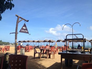 Chairs and tables at beach against sky