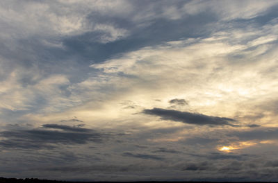 Low angle view of sunlight streaming through clouds