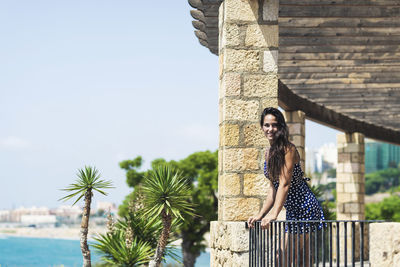 Smiling young woman standing by railing