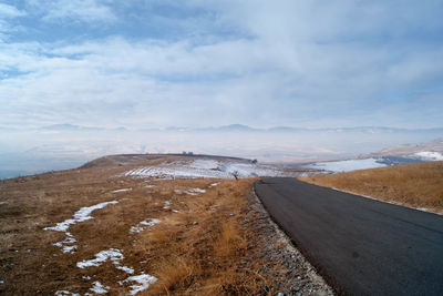 Road by mountains against sky during winter