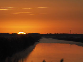 Scenic view of silhouette landscape against orange sky
