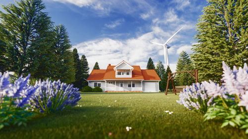 Houses and trees on field against sky