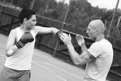 Side view of young male trainer teaching boxing to boy