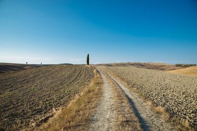 Dirt road against clear blue sky