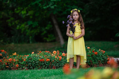 Woman standing by flowering plants on field