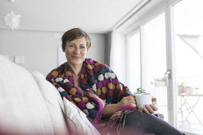 Portrait of smiling woman relaxing with cup of coffee on the couch