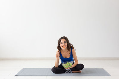 Young woman sitting on wall