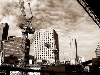 Low angle view of crane against cloudy sky