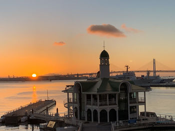 View of buildings by sea against sky during sunset