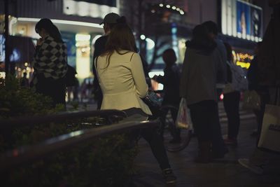 People on street against buildings at night