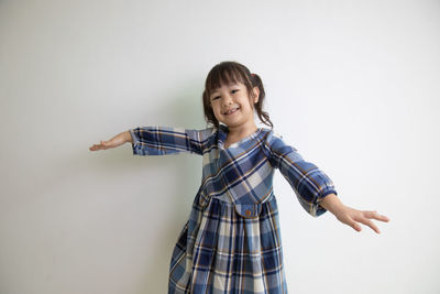 Portrait of smiling girl standing against white background