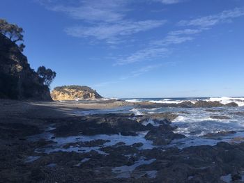 Rock formation on beach against blue sky