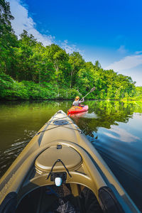 Rear view of woman canoeing on river by plants