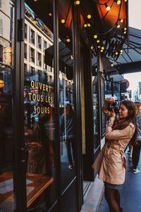 Reflection of woman photographing on glass