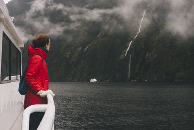 A woman stares up at the surrounding mountains in milford sound, nz