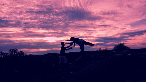 Silhouette people standing on street against sky during sunset