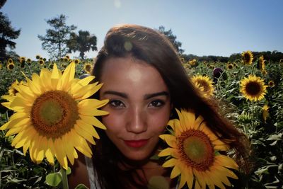 Portrait of woman with sunflowers on field