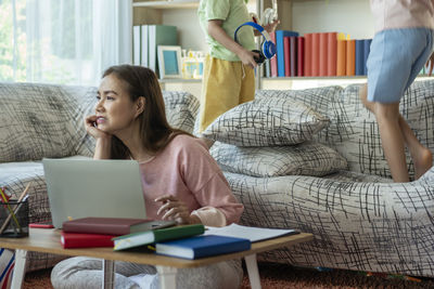Friends using laptop while sitting on sofa at home