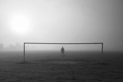 Full length of woman standing on field in foggy weather