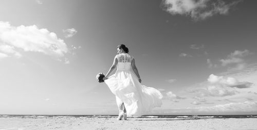 Rear view of woman on beach against sky