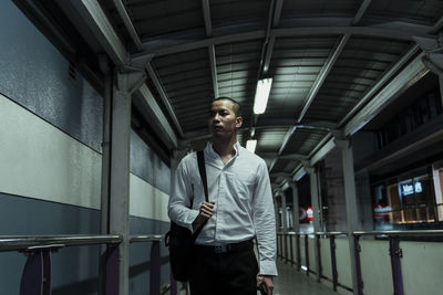 Man looking away while walking on bridge