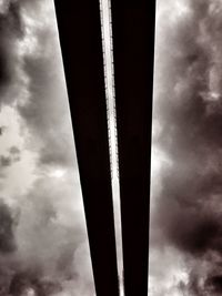 Low angle view of poles against cloudy sky