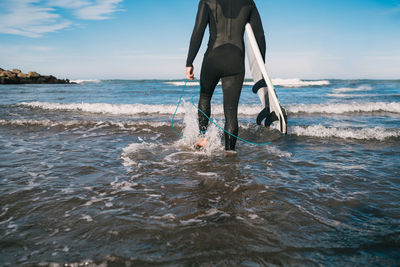 Low section of man standing on beach