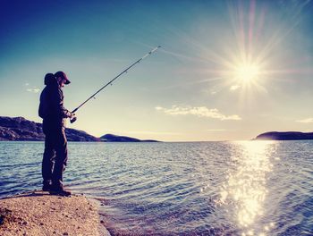 Fisherman check pushing bait on fishing line, throw lure into blue water. the active man is fishing